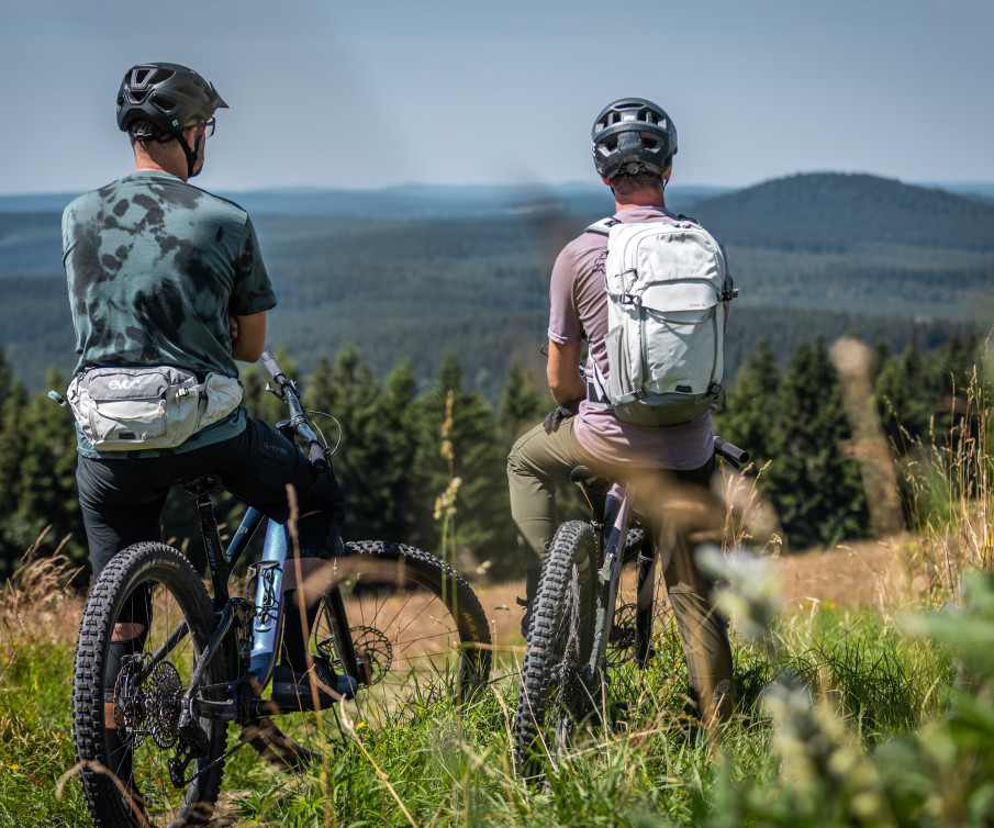 Zwei Mountainbiker von Hinten mit einer Hügellandschaft im Hintergrund