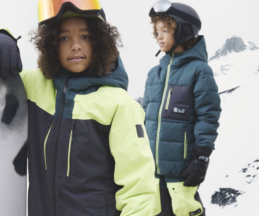 Zwei Jungen mit knallgelben Skianzügen und Helmen